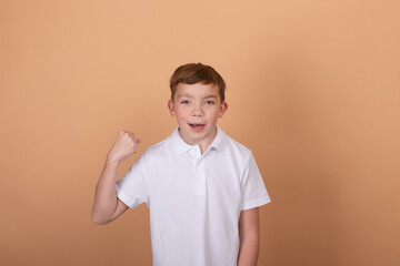 Portrait of school boy with facial expression isolated over light brown background. Concept of feelings, youth, fashion, facial expression, emotions, lifestyle, ad.