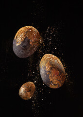 Flying easter colored eggs in purple color with gold and golden pollen on black background.Close up.Eggs in freeze motion.