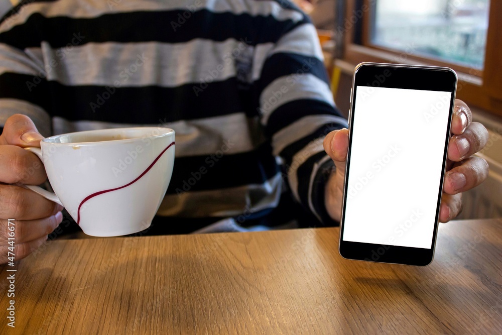 Poster man showing mobile phone with blank white screen while sitting in a cafe.
