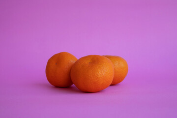 Three oranges on colour background