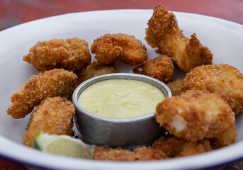 Seafood. Closeup view of fried breaded shrimps with avocado mayonnaise and lemon in a white bowl.