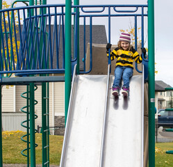 A young girl playing on a slide in a park
