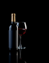 bottle and glass of red wine on a dark background with reflection