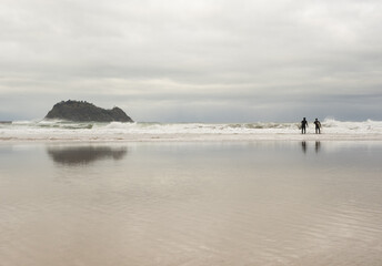 Surfers on the beach of Zarautz with Getaria in the background, Euskadi