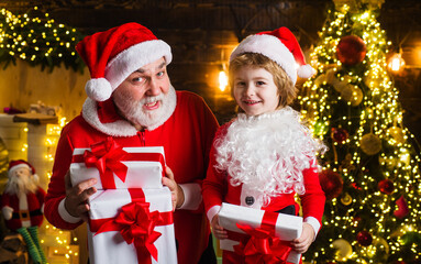 Santa Claus and little helper with Christmas present. New year gift. Happy childhood. Christmas background.