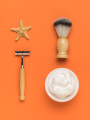 A starfish and a stylish shaving kit on an orange background. Flat lay.