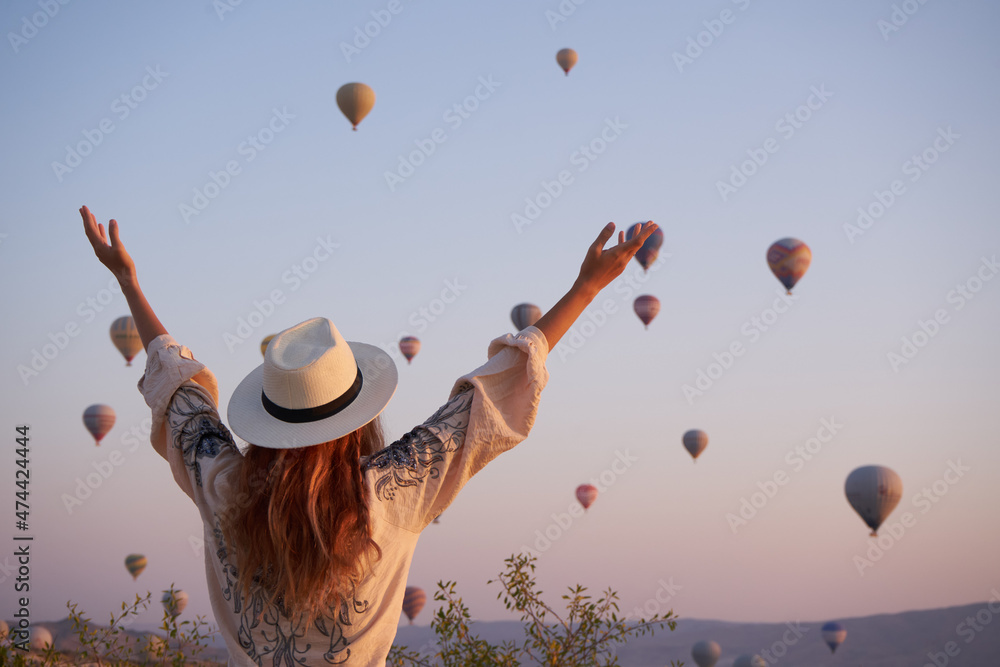 Wall mural tourist girl standing and looking to hot air balloons in cappadocia, turkey.happy travel in turkey c