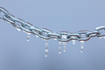Icicles on a chain, frosted metal on a light background.