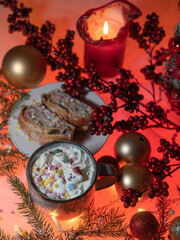 A mug of coffee, sprigs of spruce, New Year's garland, a candle on the table. Christmas decorations, Christmas still life. View from the top. Colored light. Concept, holiday, congratulations.