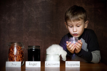 European appearance boy. In jars next to him joy, anger, laziness. In the hands of a child a jar of happiness.