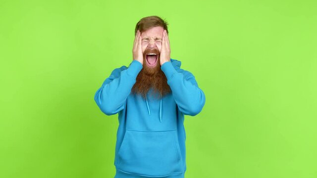 Redhead man with long beard smiling a lot while covering mouth over isolated background
