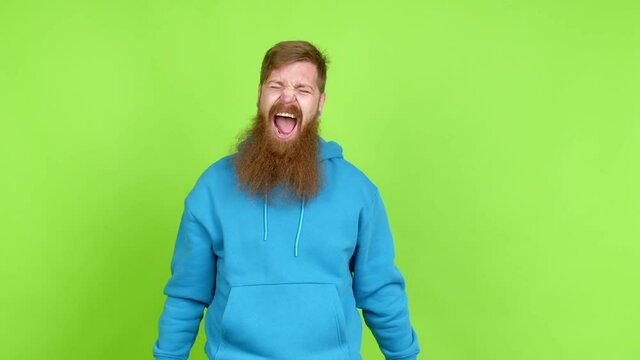 Redhead man with long beard celebrating a victory and surprised to be successful over isolated background