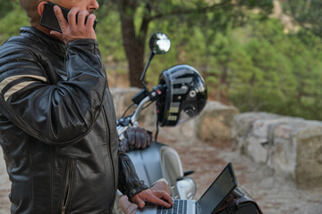 Digital nomad with laptop talking on the phone while traveling on motorcycle