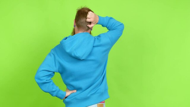 Redhead man with long beard on back position looking back while scratching head over isolated background