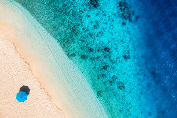 Umbrella on the beach. Beach and sand background from top view. Aerial seascape. Summer seascape from air.