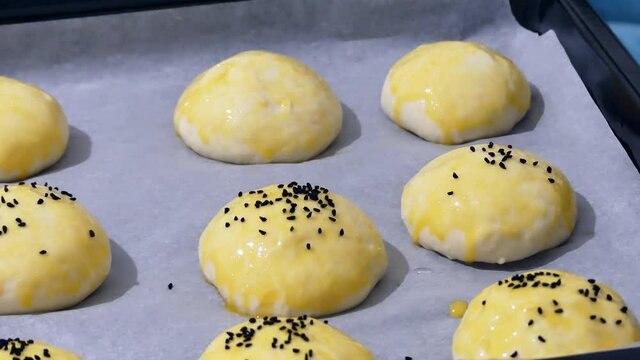 The process of sprinkling black cumin on the raw pastry dough on baking paper,