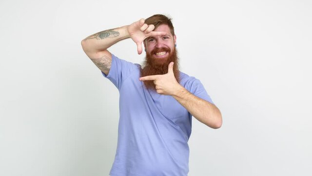 Redhead man with long beard focusing with fingers over isolated background