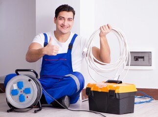 Young electrician working on socket at home