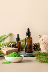 Winter Spa cosmetic care, essence oil, pine cones, evergreen branches on beige background. Close up. Special offer for beauty saloon. Vertical format.