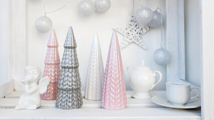 Ceramic figurines of pastel-colored Christmas trees, a white faience angel, a garland of balls made of threads decorate the room before Christmas