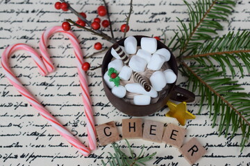 Candy canes shaped like a heart with chocolate mousse filled cup with the word cheer, berries and greenery.