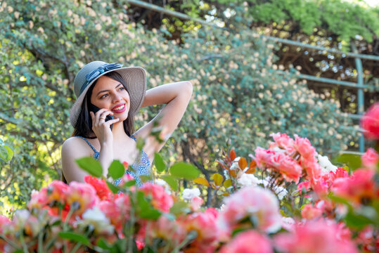Young woman talking on the phone at park during spring summer season in vacations