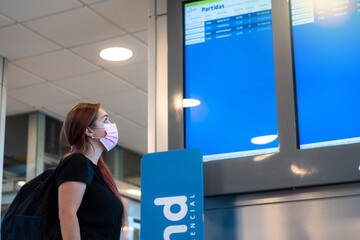 Mujer viajera buscando su vuelo en las pantallas informativas del aeropuerto
