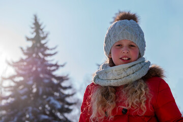 Portrait of the happy child in the winter.The girl against the background of snow.The cheerful child in warm clothes in the winter. Winter scene. Time of winter vacation.