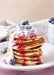 pancakes with jam, sour cream and blueberries sprinkled with powdered sugar