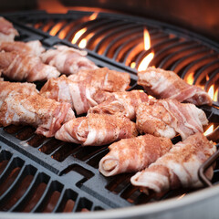 Bacon wrapped chicken wings on the grill, close up