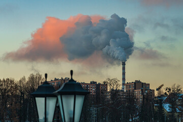 Urban winter landscape with a large chimney from which steam and smoke