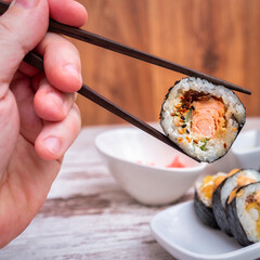 Sushi roll with salmon held on chopsticks
