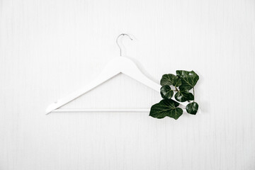 Sustainable fashion, Circular economy, eco friendly Clothing, hemp fabric cloth in Future. Wooden Clothes hanger with green leaves on white background