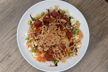 Overhead view of artistic presentation of ahi poke tuna in a deep bowl over crunchy nachos for a...