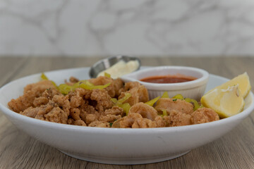 Crunchy bowl full of battered calamari rings mixed with sliced peppers, tarter, and cocktail sauce