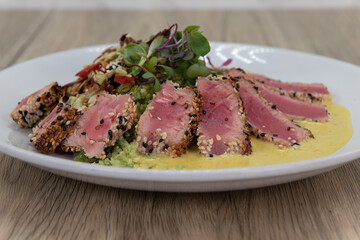 Artistic presentation of seared ahi tuna slices arranged in circular garnished plate of food