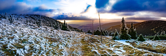 Scenic landscape with spruce trees covered with rime, view from a mounatin range to the valley.Sun behind clouds, dramatic clouds.Jeseniky.Czech republic. .