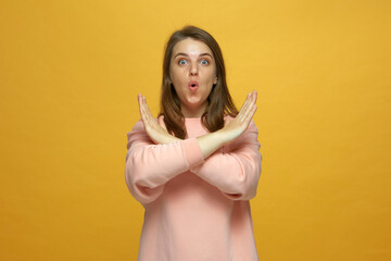 All sold out. Amazed young girl showing stop gesture crossed her palms on yellow studio background. Big sale