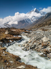 Fototapeta na wymiar Mountain river in valley in day light with view to summit in Nepal