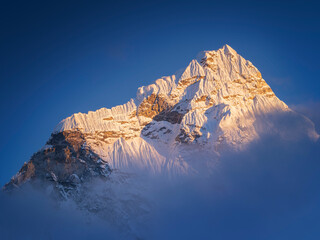 Snow peak in sun light between blue sky and clouds in Nepal