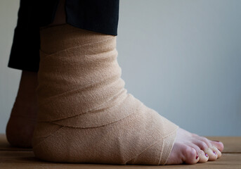 Close up of a person with a compression bandage wrapped around the foot. Concept of injury and...