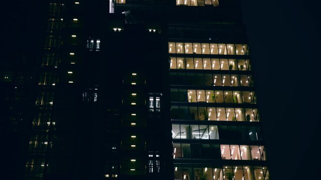 Time lapse skyscraper business center windows lights during the working day. Blinking office windows light at late night.