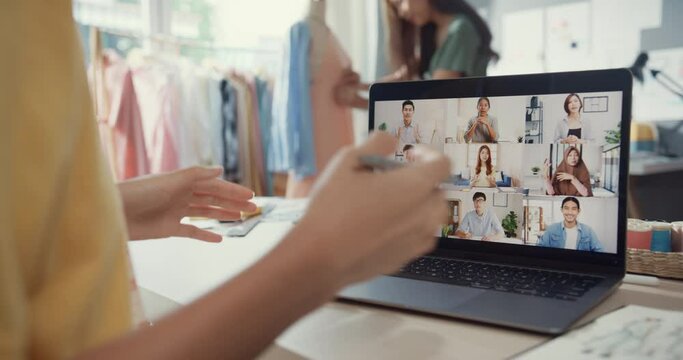 Close-up young Asia lady dressmaker use laptop on meeting with multi graphic designer team discuss sample create dress design new collection on desk in shop. Tailor new business startup concept.