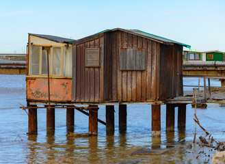 An old fishing shack of metal and wood standing in the water at the mouth of the Cornia River in...