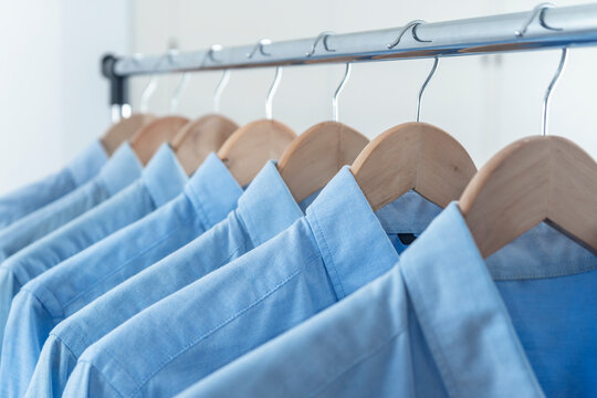 LIGHT BLUE SHIRTS HANGED IN THE CLOSET, DRESSING ROOM, BOUTIQUE OR STORE. MEN'S FASHION CONCEPT.