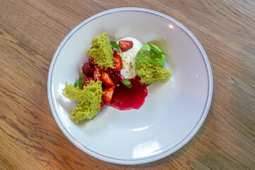 Dessert with sponge cake and strawberries is on the plate.
