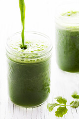 Glass jars containing fresh blended green juice and cilantro