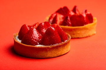 Strawberry tarts with custard on red background close-up macro