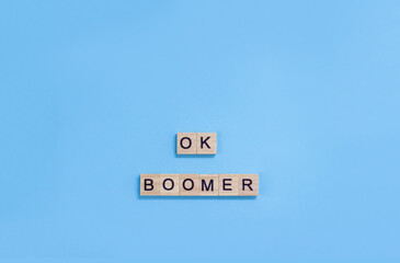 The phrase ok boomer. Wooden blocks with letters on a blue background. Age discrimination concept....