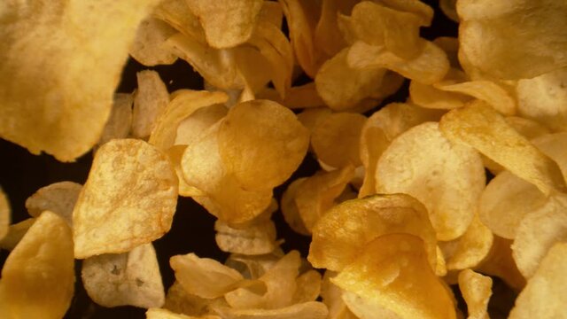 Super Slow Motion Detail Shot of Potato Chips Falling on Black Background at 1000fps.